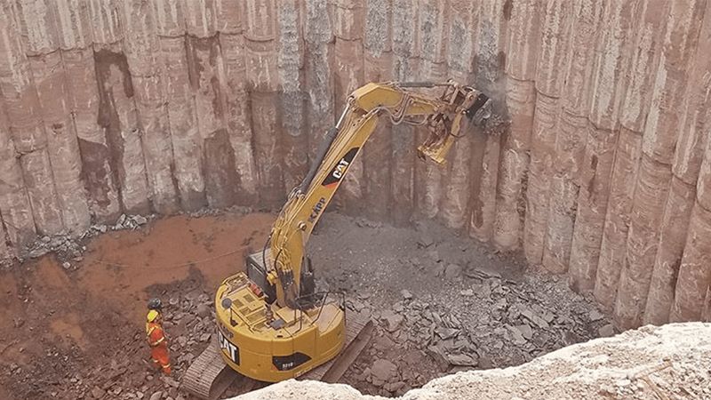 An Excavator Equipped With A Rockwheel Trimming A Secant Pile Wall